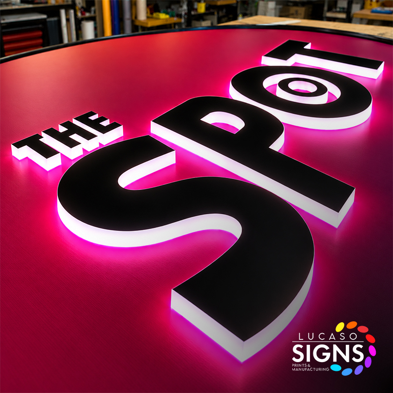 Custom illuminated push-through acrylic letters with black faces and bright pink LED glowing edges on a red sign panel